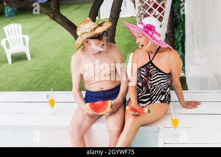 Ein glückliches Seniorenpaar, das im Pool gefeiert hat - ältere Freunde, die während der Sommerferien auf einer Poolparty ihre Ferien verbracht haben Stockfoto