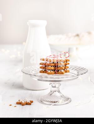 Ein Stapel von Schneeflocken Lebkuchen Kekse mit einer Schnur und einer Flasche Milch auf einem hellen weißen Hintergrund gebunden. Das traditionelle Geschenk für den Weihnachtsmann auf Chr. Stockfoto