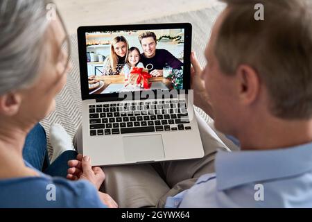 Großeltern telefonieren mit Familie und Enkelkind auf dem Laptop-Bildschirm. Stockfoto