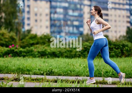 Aktive junge schlanke Frau läuft im Park in Sportkleidung. Stockfoto