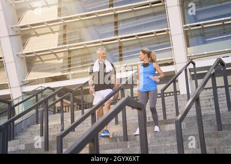 Aktives, sportliches reifes Paar, Mann und Frau in Sportkleidung, die nach dem gemeinsamen Training im Freien die Treppe hinunter gehen Stockfoto