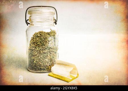 Getrocknetes Marihuana in einem Glas und Rollen Sie Ihr eigenes Papier Stockfoto