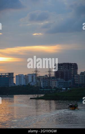 Blick auf den See von Dhaka City mit Skyline Gebäuden am Abend. Sonnenlicht, das sich im Wasser des Sees widerspiegelt. Stockfoto