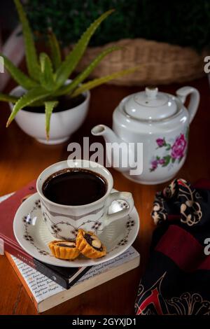 Eine Tasse schwarzen Kaffee mit einem Hintergrund aus Aloe Vera Blumen als Ergänzung zum Foto Stockfoto