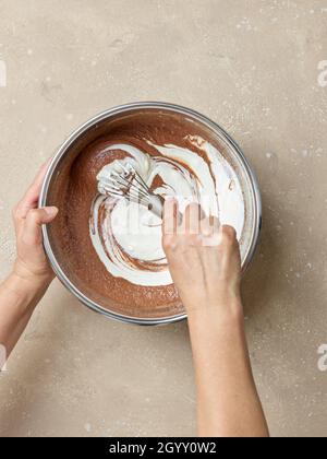 Schokoladenkuchen Teig Herstellung Prozess, Mischen Joghurt in den Teig, Draufsicht Stockfoto