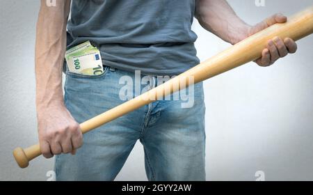 Mann mit Euroscheinen in der Tasche, der einen Baseballschläger in den Händen hält - bedrohlich. Stockfoto