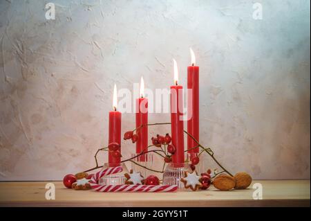 Vier angezündete rote Kerzen für den vierten Sonntag vor Weihnachten, Adventsdekoration auf einem Holztisch an einer rustikalen Wand, Kopierraum, ausgewählter Fokus, na Stockfoto