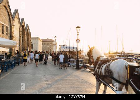 Touristen, die bei Sonnenuntergang auf der Uferpromenade in der Altstadt von Chania, Kreta, Griechenland, spazieren gehen Stockfoto