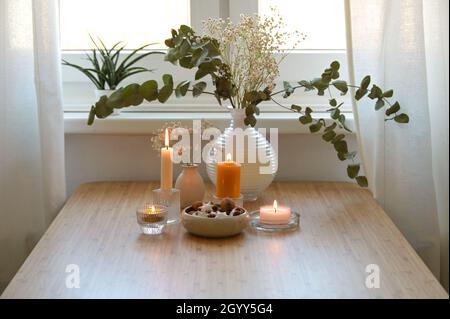 Vier verschiedene goldene brennende Kerzen, Vase mit Eukalyptuszweigen und eine Schale mit Keksen, festliche Dekoration für Advent und Weihnachten auf einem Holz Stockfoto