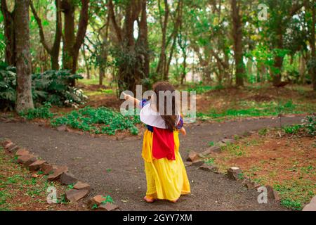 Ein süßes kleines hispanische Mädchen, das ein schneeweißes Kleid als Halloween Kostüm in einem Wald trägt Stockfoto