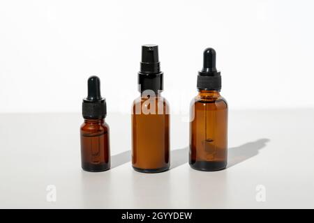 Set von nicht gebrandeten dunklen Glasflaschen für Design. Ätherisches Öl, Gesichtsserum und Creme in Mock-up-Paket. Minimalistischer Style. Trendiges Konzept. Stockfoto