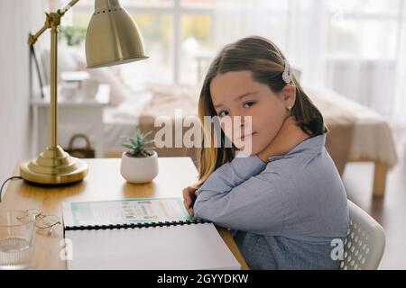 Portrait Schule Mädchen sitzt am Schreibtisch machen Hausaufgaben. Home Schooling, Fernschulkonzeptschule und Home Schooling, Fernschulbildung Co Stockfoto