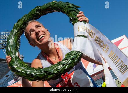 München, Deutschland. Oktober 2021. Corinna Harrer hält einen Lorbeerkranz und jubelt nach ihrem Sieg beim Münchner Marathon 2021 im Olympiastadion. Der ehemalige Mittelstreckenspezialist lief in 2:43:11 Stunden die Strecke zwischen dem Olympiastadion und dem Englischen Garten. Kredit: Peter Kneffel/dpa/Alamy Live Nachrichten Stockfoto