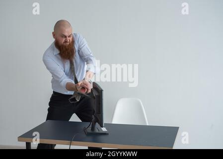 Gestresste verrückte Geschäftsmann zerschlagen seinen Computer im Büro mit Axt Problem Konzept. Der Mann hat Probleme bei der Arbeit und Frustration. Stockfoto