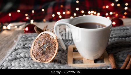 Weihnachtliche Komposition mit einer Tasse Tee, getrockneten Orangen, Gewürzen auf verschwommenem Hintergrund. Stockfoto