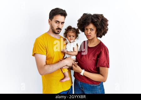 Interracial junge Familie von schwarzer Mutter und hispanischen Vater mit Tochter skeptisch und nervös, runzelte wegen des Problems. Negative Person. Stockfoto