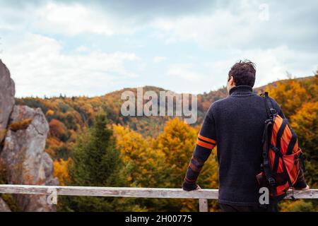 Mann Reisende mit Rucksack steht bei Felsen in Tustan im Herbst Karpaten Berge. Tourismus im Herbst Ukraine. Wandern und Erholung Stockfoto
