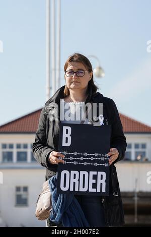 Sopot, Polen 10. Oktober 2021 in Sopot, Polen, wird am 10. Oktober 2021 ein Protestler mit dem als Stacheldraht stilisierten „Grenzbanner“ in Form einer weißrussischen Stickerei gesehen, bei dem die Menschen unter dem Motto protestieren: Bringen Sie die Kinder nicht in den Wald. Sie protestieren gegen die Politik der polnischen Regierung, Flüchtlinge aus dem Irak, Afghanistan und anderen Ländern, die mit kleinen Kindern aus Belarus in den Wald an der Grenze zu Belarus kommen, zu drängen. Die polnische Regierung verweigert ihnen internationalen Schutz und transportiert sie illegal in den Wald, um sie ins Ausland zu drängen. Quelle: Vadim Pacajev/Alamy L. Stockfoto