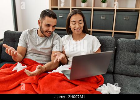 Junge lateinamerikanische kranke Paare, die zu Hause eine medizinische Fernsulation mit einem Laptop haben. Stockfoto