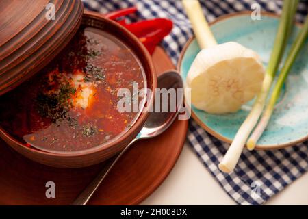 Ukrainischer Rotborsch mit saurer Rahm, Knoblauch und grünen Zwiebeln. Erster Gang. Abendessen. Ein traditionelles Gericht. Ukrainisches Essen auf dem Tisch. Stockfoto