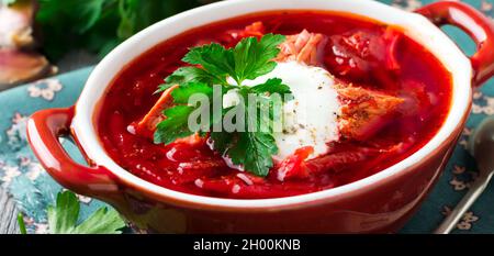 Rote Beete Suppe mit Fleisch, saurer Rahm und Petersilie in einer braunen Keramikschale auf dem alten Holzhintergrund. Borsch - traditionelles Gericht der ukrainischen Küche. S Stockfoto