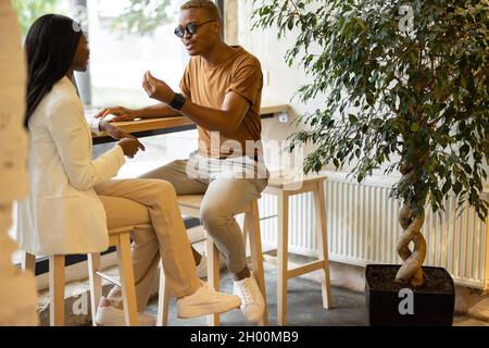 Mann, der der Frau im Café etwas erzählt Stockfoto