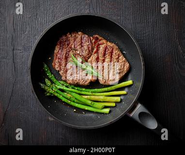 Gegrilltes Entrecote-Steak, Spargel und Rosmarin auf der Kochpfanne, Draufsicht Stockfoto