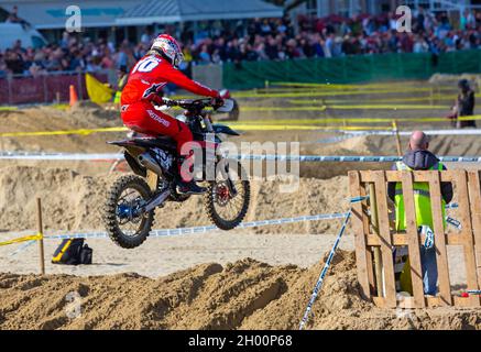 Weymouth, Dorset, Großbritannien. 10.. Oktober 2021. Tausende von Zuschauern strömen nach Weymouth, um den Reitern beim jährlichen Motocross-Rennen am Weymouth Beach zuzusehen. Etwa 300 Fahrer fahren mit hoher Geschwindigkeit und geschicktem Manövrieren um die Hindernisstrecke, während die Menschenmassen die Action beobachten, dem Dröhnen der Motoren und dem Geruch der Motorräder lauschen. . Kredit: Carolyn Jenkins/Alamy Live News Stockfoto