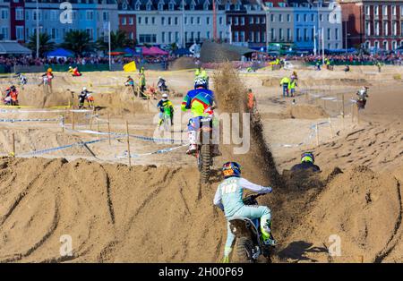 Weymouth, Dorset, Großbritannien. 10.. Oktober 2021. Tausende von Zuschauern strömen nach Weymouth, um den Reitern beim jährlichen Motocross-Rennen am Weymouth Beach zuzusehen. Etwa 300 Fahrer fahren mit hoher Geschwindigkeit und geschicktem Manövrieren um die Hindernisstrecke, während die Menschenmassen die Action beobachten, dem Dröhnen der Motoren und dem Geruch der Motorräder lauschen. . Kredit: Carolyn Jenkins/Alamy Live News Stockfoto