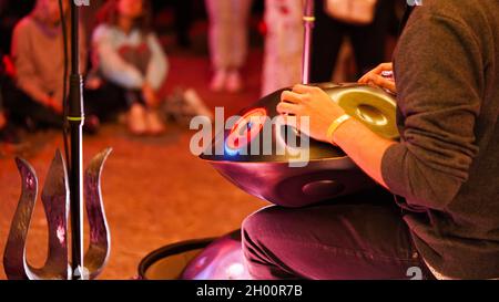 Nahaufnahme von männlichen Händen, die ein Handpan-Musikinstrument spielen, Handtrommel bei einem Konzert mit ethnischer Musik. Entspannung, folkloristische, meditative und traditionelle ethnische Musik Stockfoto