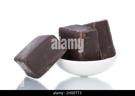 Drei süße Schokoladen-Bonbons auf einer weißen Keramikuntertasse, Nahaufnahme, isoliert auf Weiß. Stockfoto