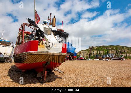 Fischerboote am Kiesstrand an der Küste von Hastings in East Sussex, England, mit der Standseilbahn in der Ferne Stockfoto