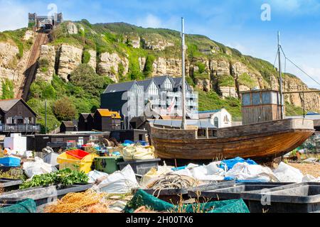 Fischerboote am Kiesstrand an der Küste von Hastings in East Sussex, England, mit der Standseilbahn in der Ferne Stockfoto