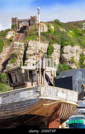 Fischerboote am Kiesstrand an der Küste von Hastings in East Sussex, England, mit der Standseilbahn in der Ferne Stockfoto