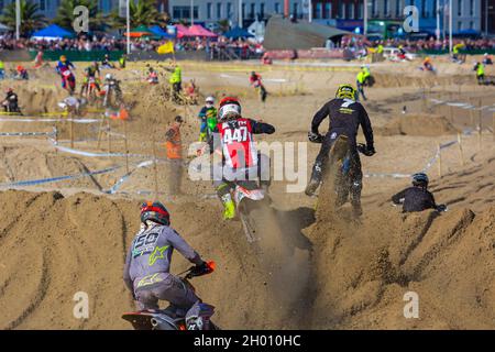 Weymouth, Dorset, Großbritannien. 10.. Oktober 2021. Tausende von Zuschauern strömen nach Weymouth, um den Reitern beim jährlichen Motocross-Rennen am Weymouth Beach zuzusehen. Etwa 300 Fahrer fahren mit hoher Geschwindigkeit und geschicktem Manövrieren um die Hindernisstrecke, während die Menschenmassen die Action beobachten, dem Dröhnen der Motoren und dem Geruch der Motorräder lauschen. . Kredit: Carolyn Jenkins/Alamy Live News Stockfoto