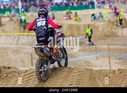 Weymouth, Dorset, Großbritannien. 10.. Oktober 2021. Tausende von Zuschauern strömen nach Weymouth, um den Reitern beim jährlichen Motocross-Rennen am Weymouth Beach zuzusehen. Etwa 300 Fahrer fahren mit hoher Geschwindigkeit und geschicktem Manövrieren um die Hindernisstrecke, während die Menschenmassen die Action beobachten, dem Dröhnen der Motoren und dem Geruch der Motorräder lauschen. . Kredit: Carolyn Jenkins/Alamy Live News Stockfoto