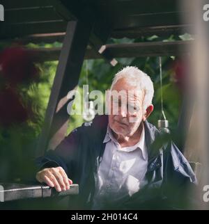 Porträt eines alten traurigen Mannes mit deprimiertem Gesichtsausdruck, der auf einer Bank im Park sitzt Stockfoto