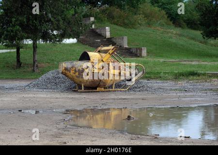 Alte rostige mobile Betonmischer auf der Straße. Gelber Betonmischer. Metallausrüstung für Bauzwecke. Stockfoto