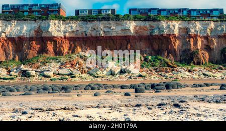 Moderne Wohnungen scheinen sich gefährlich nahe am Rand der berühmten erodierenden rotbraunen Steinklippen in Hunstanton, Norfolk, Großbritannien, zu befinden. Stockfoto