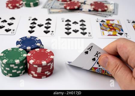 Spielkarten und Casino-Chips auf weißem Hintergrund isoliert. Mann, der Casino High Hand Karten ansieht. Stockfoto