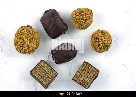 Süßigkeiten mit Nüssen, Waffeln und Schokolade auf weißem Hintergrund von oben. Köstliche süße Desserts mit Schokolade. Hausgemachte Süßigkeiten. Stockfoto