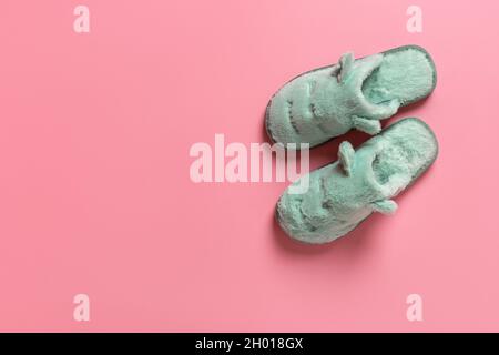 Böse Katze Gesicht Hausschuhe über rosa Korallen Hintergrund mit Kopie cpace. Neues Paar hellgrüne gemütliche Hausschuhen für die kalte Wintersaison. Lustige Heimschuhe Stockfoto
