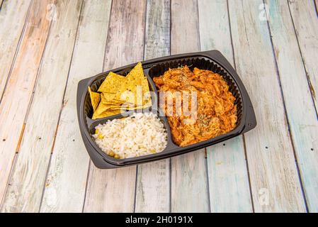 Mexikanisches Hähnchen Tinga Eintopf zum Mitnehmen mit weißem Reis, Maischips, Erbsen und süßem Mais Stockfoto