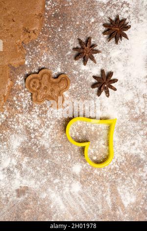 Lebkuchenmännchen-Keks, drei-Sterne-Anis-Früchte, Ausstechform in Herzform und ein Stück ausgerollter Lebkuchensüßer Teig... Stockfoto