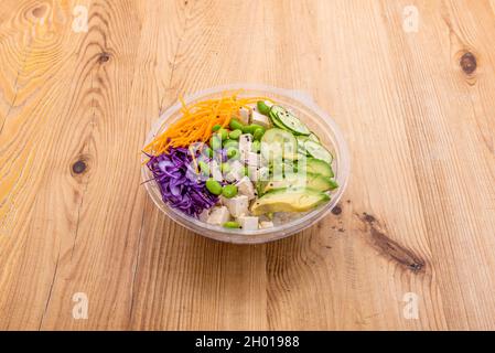 Vegane Schüssel mit Taco Tofu, weißem Reis, reifen Avocado-Brocken, edamamen Bohnen, Rotkohl und geriebenem Karotten auf einem Take-Away-Behälter Stockfoto