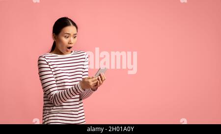 Schlechte Nachricht. Junge asiatische Frau Blick auf Smartphone mit Schock, Lesen unangenehme SMS, Porträt der emotionalen koreanischen Frau mit Mobiltelefon in den Händen S Stockfoto
