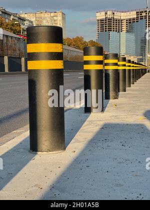 Vertikale Aufnahme von schwarzen Einzäunungen Poller Reihen schützenden Bürgersteig von Autos Stockfoto