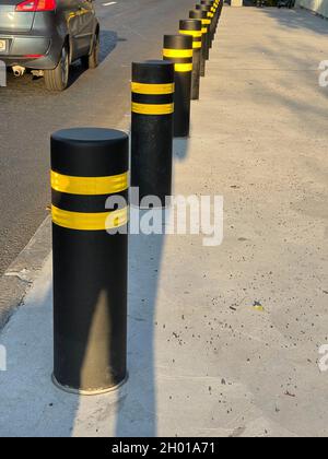 Vertikale Aufnahme von Pollern auf der Verkehrsstraße, die den Fußgängerweg schützen Stockfoto