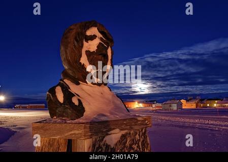 Schneebedeckte Statue von Amundsen in der dunklen Jahreszeit auf Spitzbergen. Ny Ålesund, Svalbard, Norwegen Stockfoto