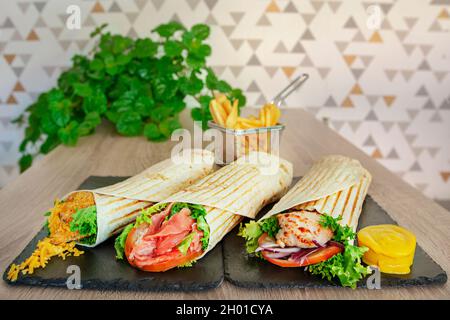 Auswahl an Wraps gefüllt mit gebratenem Huhn mit Gemüse und Senfsauce, rote Zwiebel und frischen Salat, gebratenen Fisch mit Chedd geschlagen Stockfoto